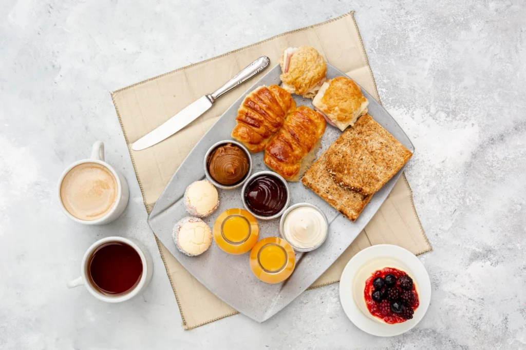 Assorted breakfast pastries, including croissants, danishes, and muffins, fresh out of the oven, golden and flaky.