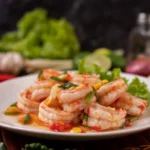 Garlic shrimp cooked in olive oil, garnished with fresh parsley and served in a white dish.