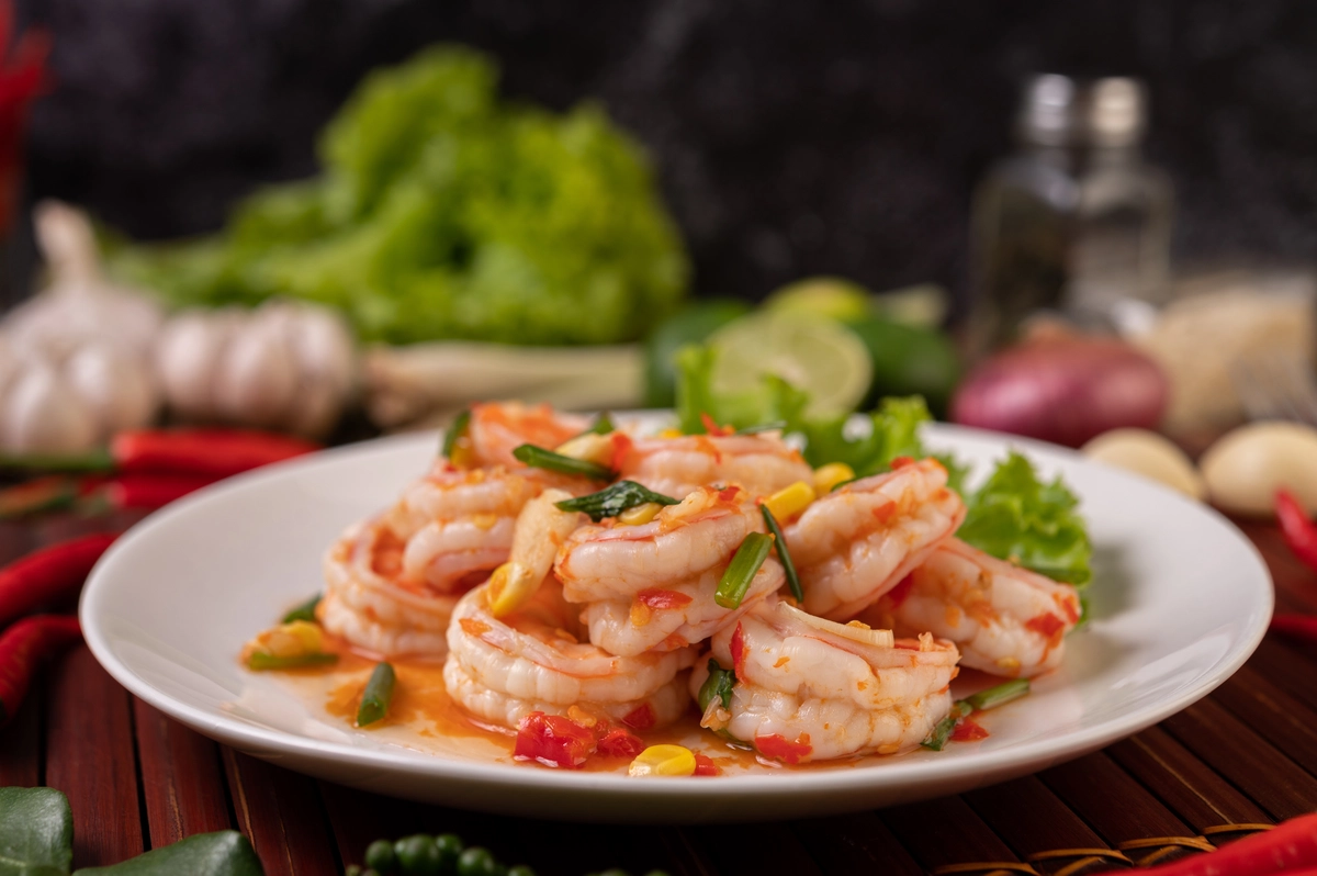 Garlic shrimp cooked in olive oil, garnished with fresh parsley and served in a white dish.