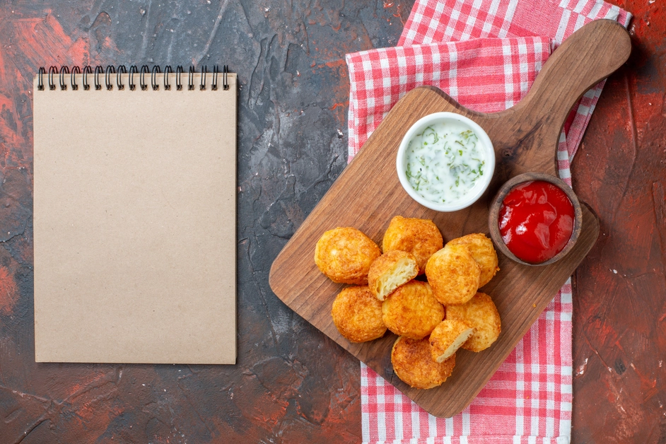 Spicy chicken nuggets in a bowl with a side of creamy ranch dipping sauce.