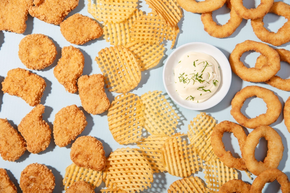 Chicken nuggets shaped like stars and dinosaurs on a colorful plate with a smiley face.