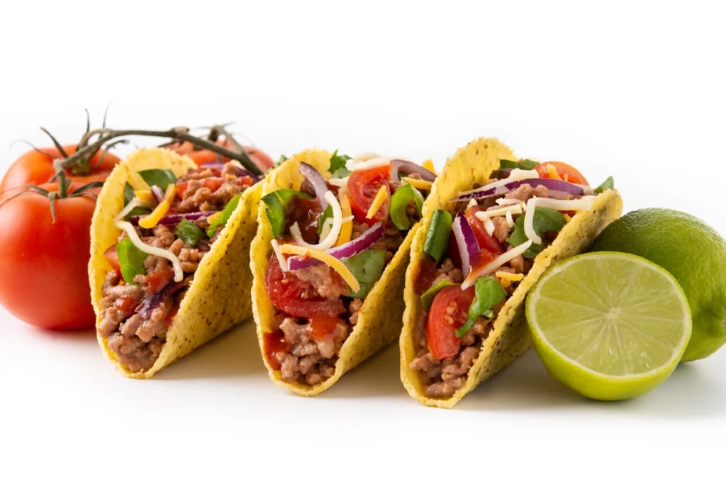 Close-up of tacos de lengua garnished with salsa verde and lime slices.