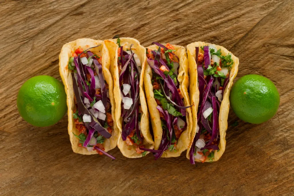 Street-style tacos de lengua paired with a side of pickled onions and a cold drink.