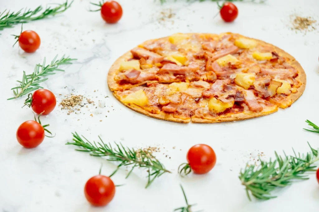 A sliced canned chicken pizza crust topped with pepperoni, cheese, and basil on a rustic wooden board