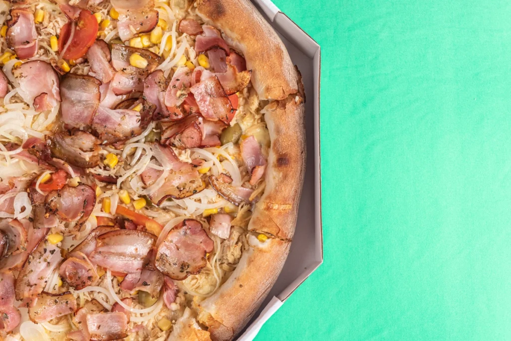 A golden canned chicken pizza crust being prepared with fresh toppings in a modern kitchen.