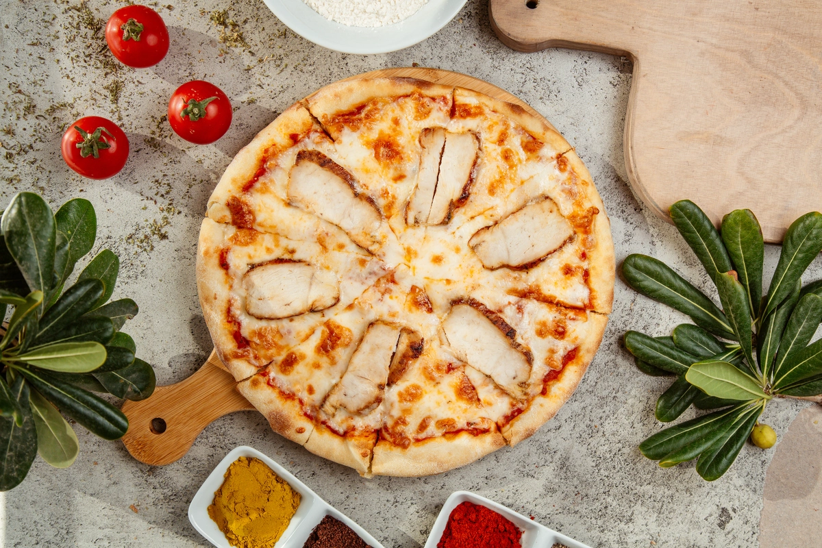 Close-up of a crispy canned chicken pizza crust topped with melted cheese and fresh vegetables.