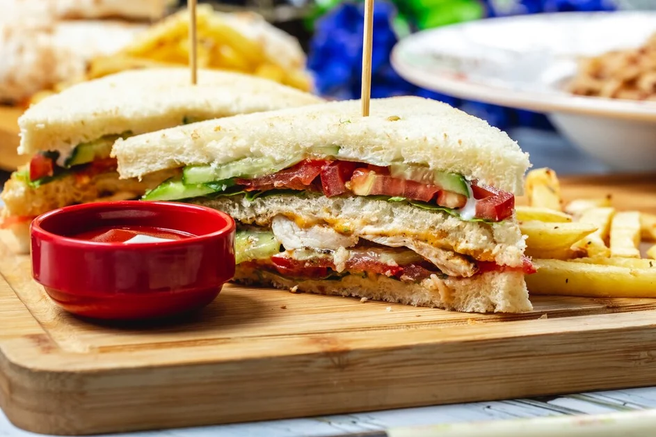 Close-up of a chicken cutlet sandwich with melted cheese and tangy pickles on toasted ciabatta bread.