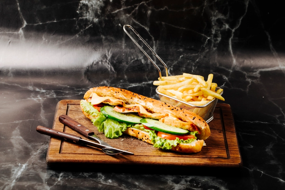 Golden breaded chicken cutlet sandwich with lettuce, tomato, and pickles on a brioche bun.