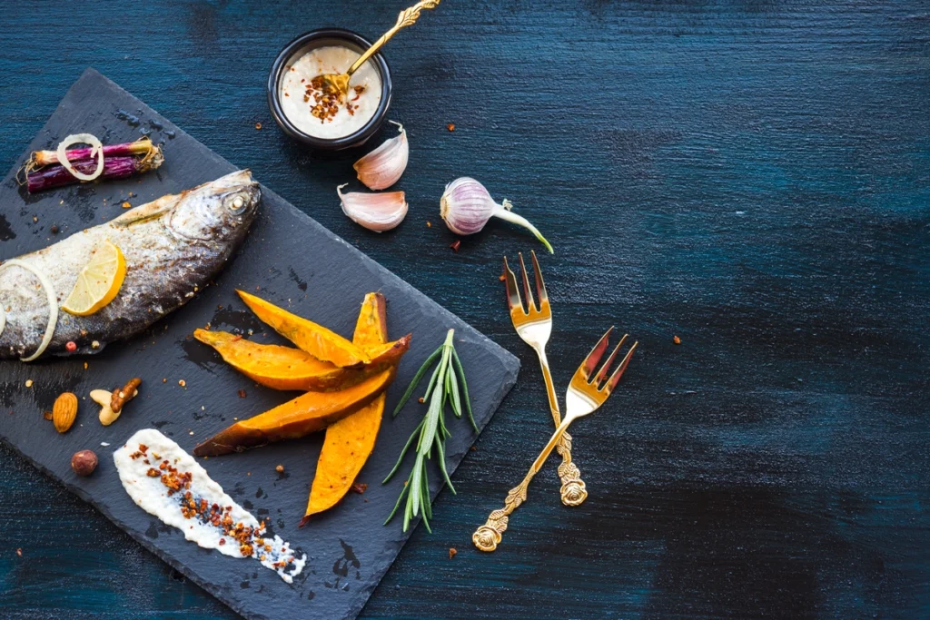 Healthy fish food recipe featuring grilled tilapia with a side of roasted sweet potatoes and sautéed greens.