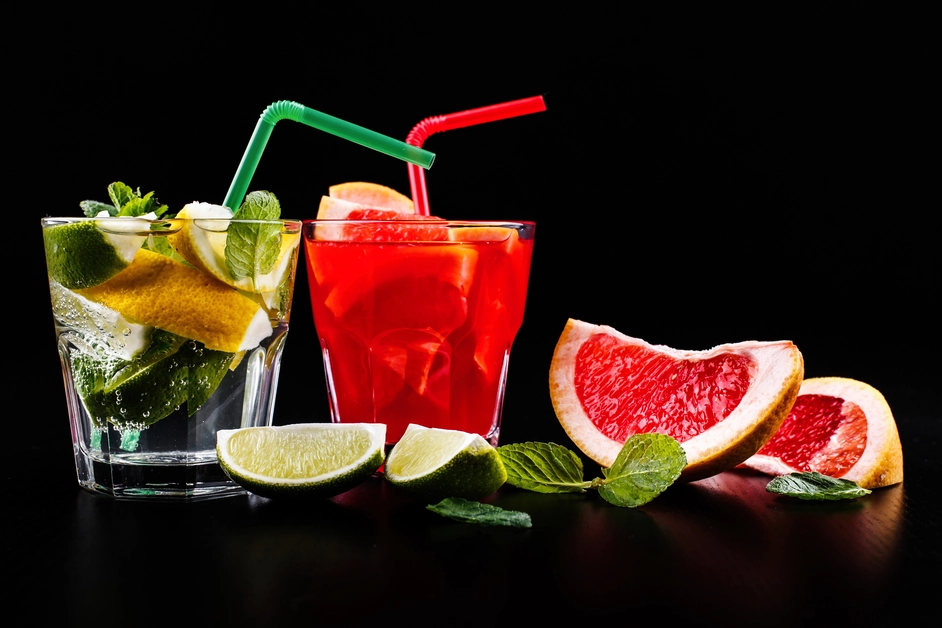 A rustic wooden tray with mason jars of Happy Juice in green, yellow, red, and orange hues, surrounded by fresh fruits.