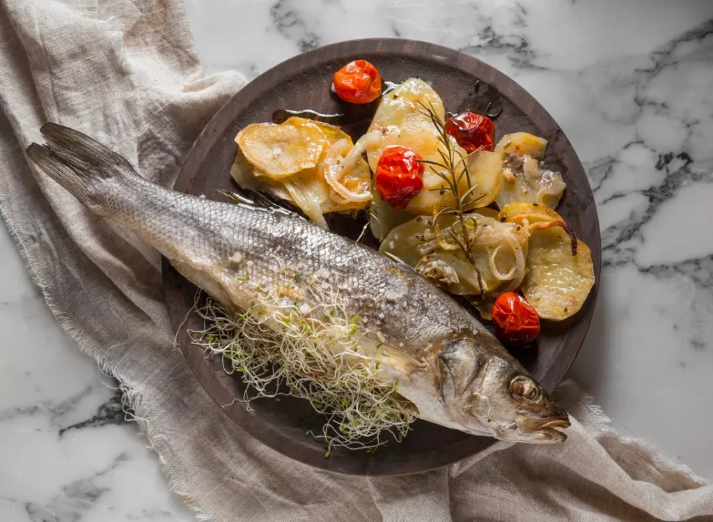 A beautifully plated Loup de Mer dish with roasted vegetables and a side of sauce.