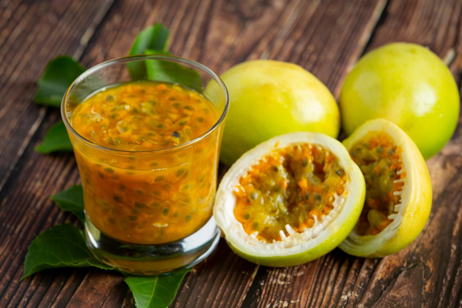 A refreshing glass of passion fruit juice with ice cubes and mint leaves.