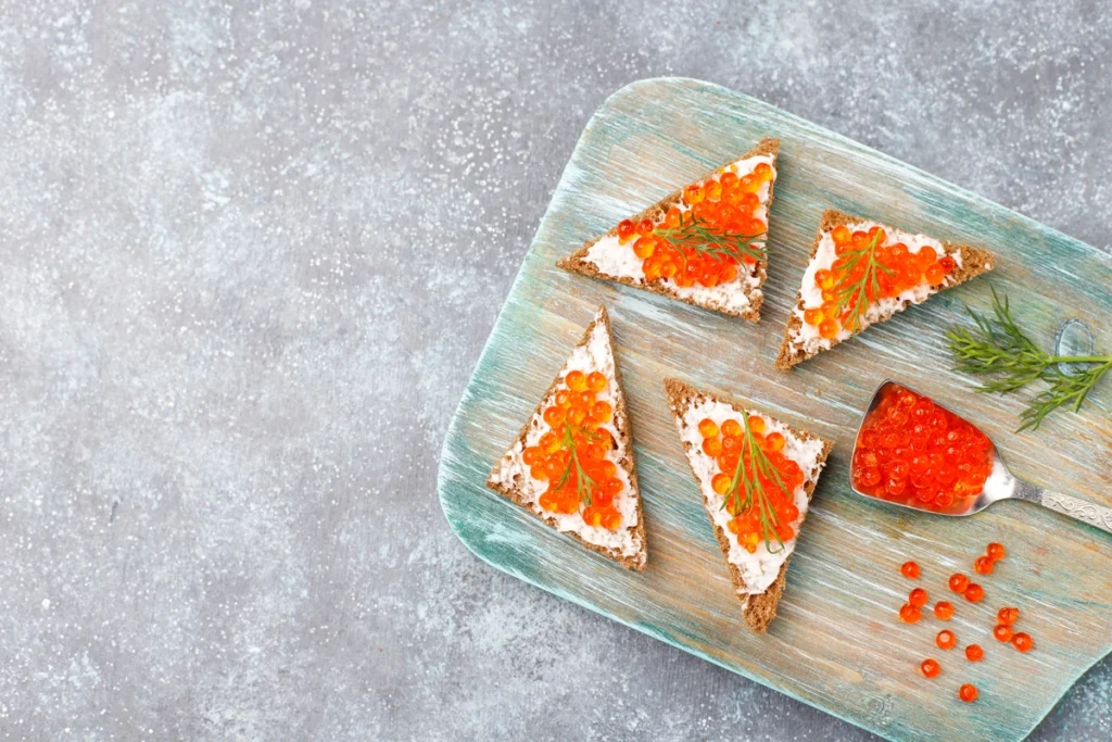 Close-up of fresh salmon roe garnished on a sushi roll.