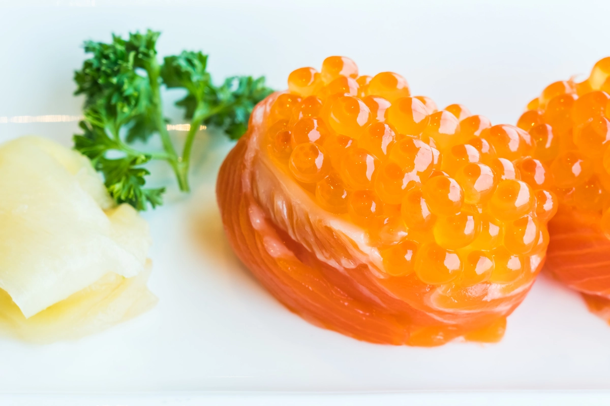 Fresh salmon roe served on sushi with a vibrant orange color.