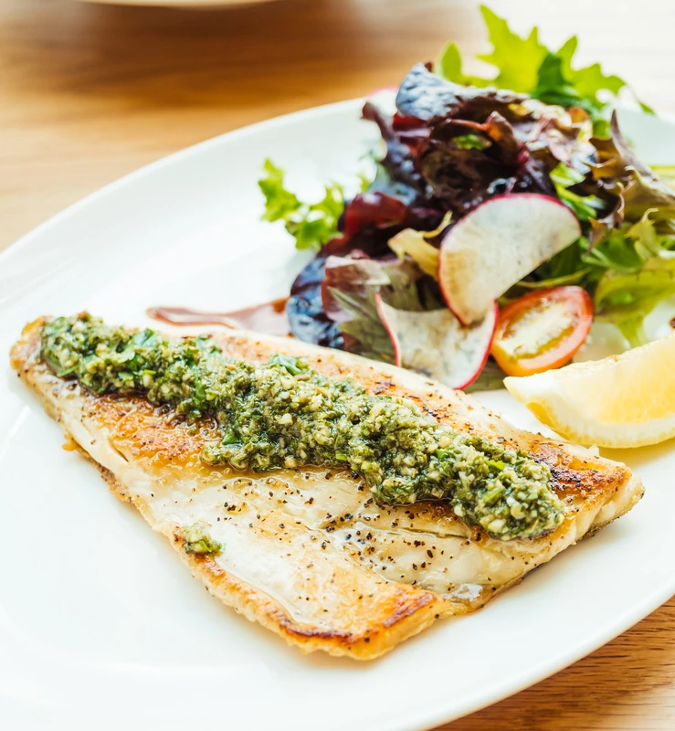 Whole sand dabs displayed on a bed of crushed ice at a seafood market, showcasing their fresh, shiny skin.