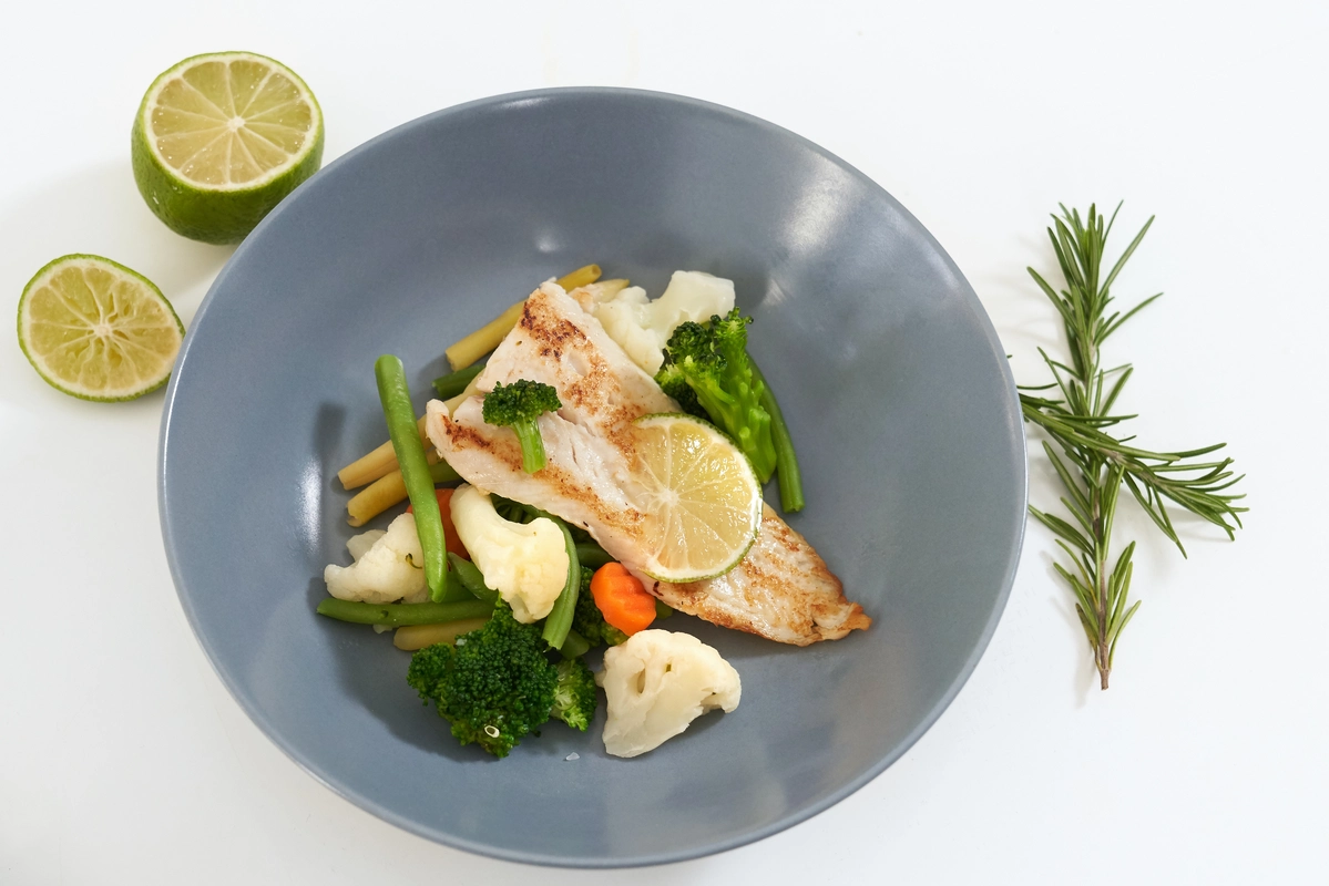 A close-up of freshly cooked pan-seared sand dabs garnished with lemon slices and parsley on a white plate.