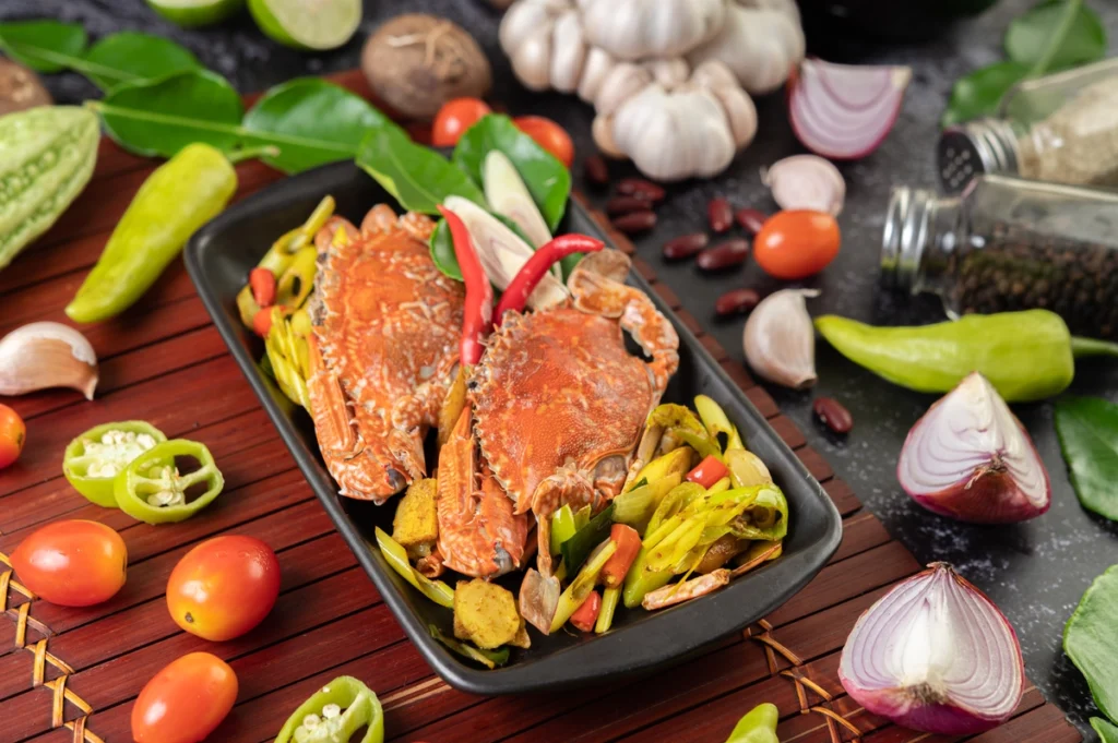 Fresh crab meat, breadcrumbs, onions, peppers, and spices displayed on a wooden cutting board.